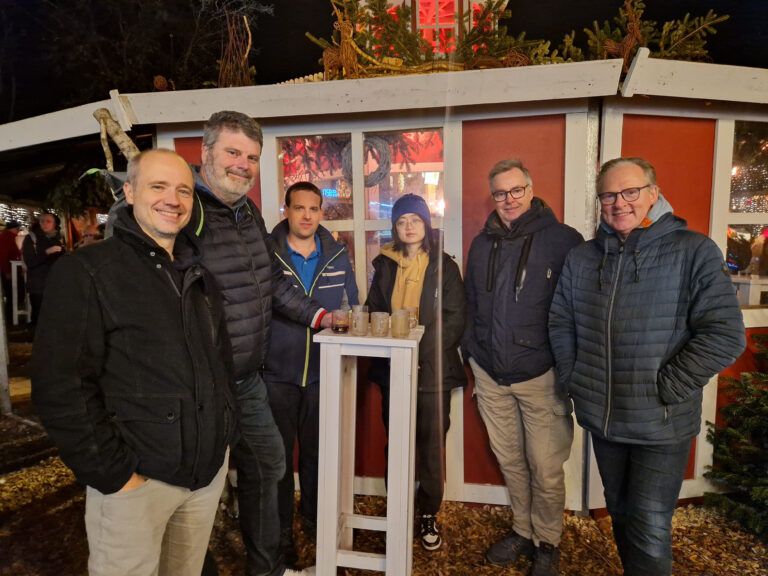 Gruppenfoto des Teams von ZewaTec Automation am Abend an einem Stand auf einem Weihnachtsmarkt