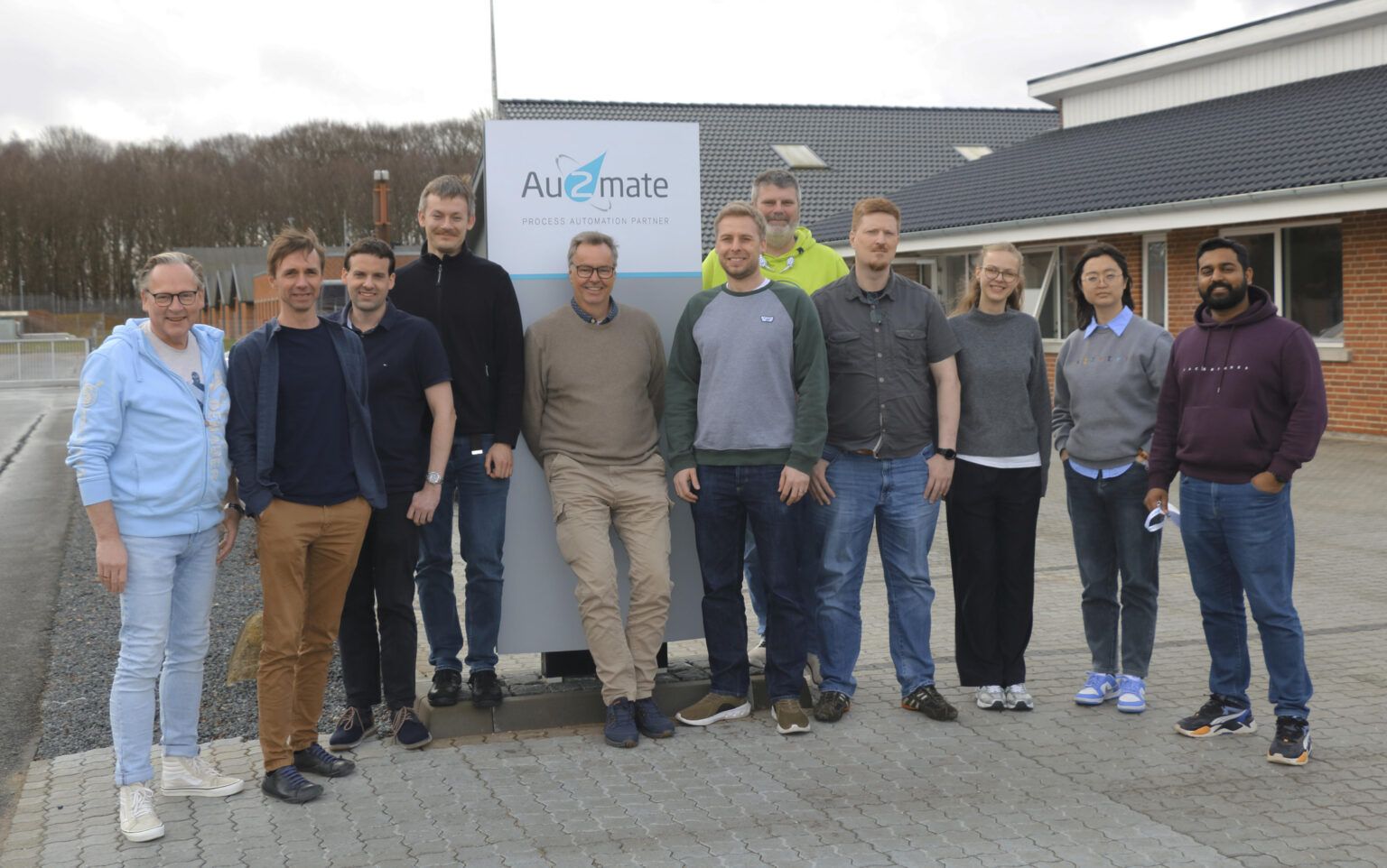 Gruppenfoto der Teams von ZewaTec Automation und Au2mate vor dem Au2mate-Schild in Silkeborg
